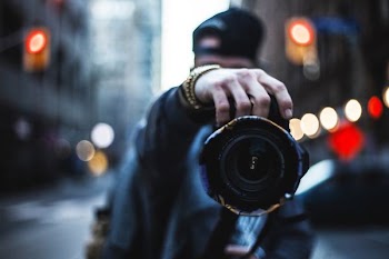 selective focus photography of man holding a camera at the street