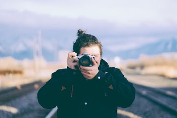 selective focus photography of man holding camera taking photo