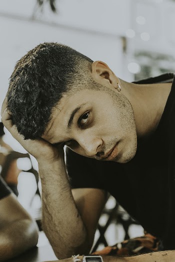 Selective Focus Photography of Man Leaning His Head on His Right Hand