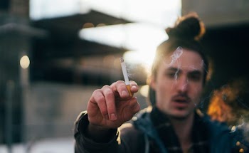 selective focus photography of man raising lighted cigarette