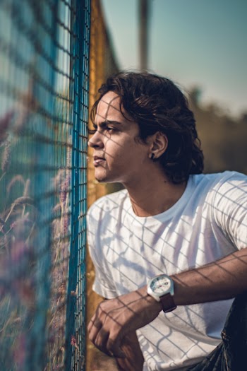 Selective Focus Photography of Man Sitting Beside Blue Railings