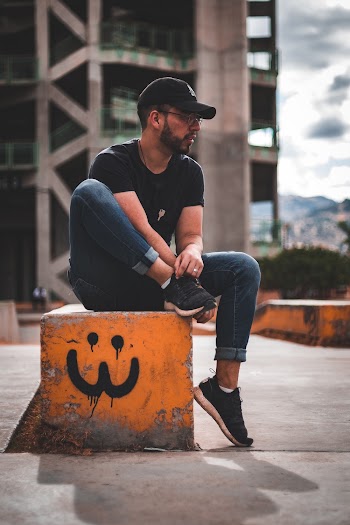 Selective Focus Photography of Man Sitting on Concrete Bench