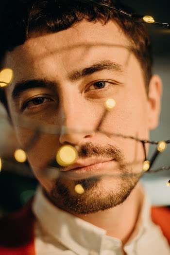 Selective Focus Photography of Man Standing Behind String Lights