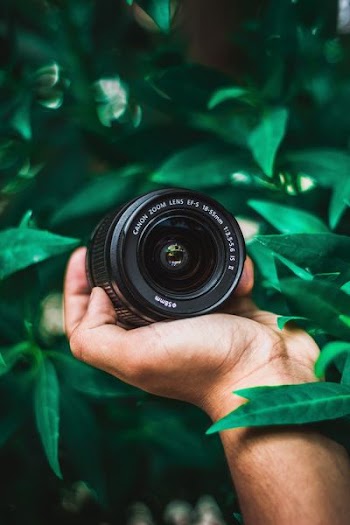 selective focus photography of person holding Canon telephoto lens