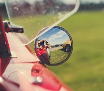 Selective Focus Photography Of Person Taking Photo On Vehicle Side Mirror