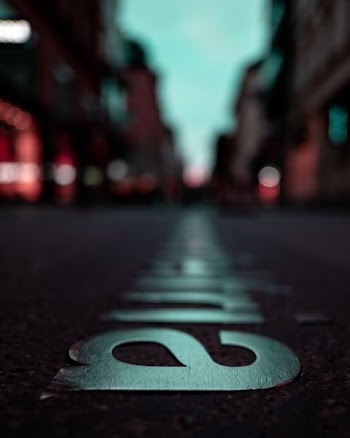 selective focus photography of silver-colored emblem on concrete pavement