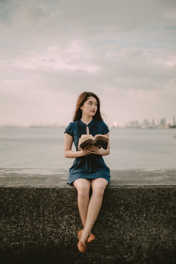 Selective Focus Photography of Sitting Woman Holding Open Book