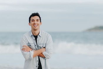selective focus photography of smiling man standing in front of sea
