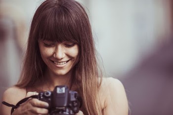 selective focus photography of smiling woman holding camera