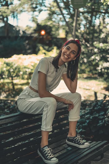 Selective Focus Photography of Smiling Woman Sitting on Brown Wooden Bench