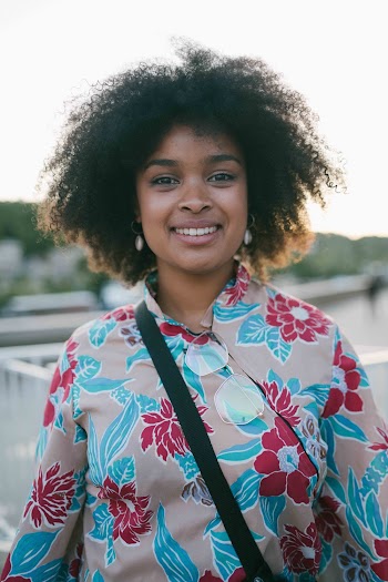 Selective Focus Photography of Smiling Woman Wearing Gray and Blue Floral Shirt Carrying Black Bag