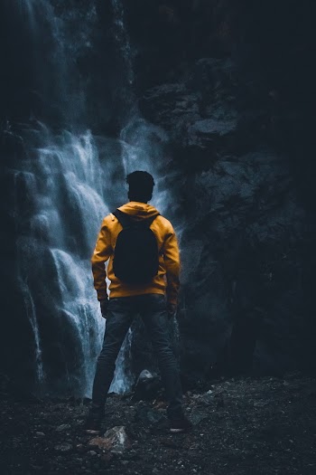 Selective Focus Photography of Standing Man in Front of Waterfalls