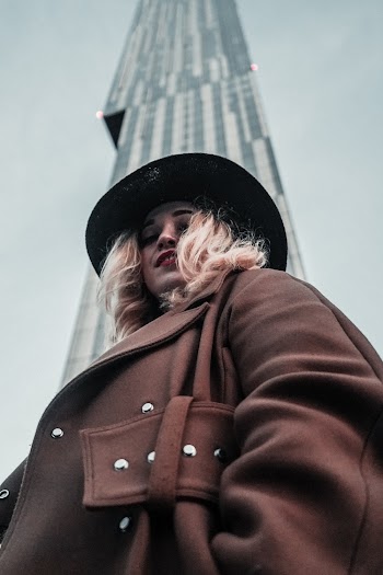 Selective Focus Photography of Standing Woman in Front of Gray Building