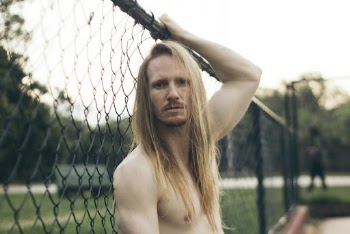 Selective Focus Photography of Topless Man Holding Fence