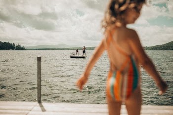 selective focus photography of two person standing on platform on body of water