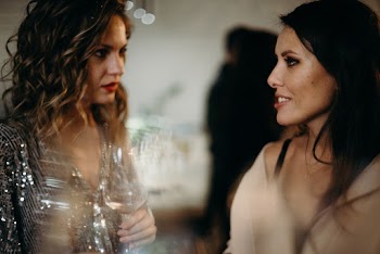 Selective Focus Photography of Two Talking Women Holding Wine Glass