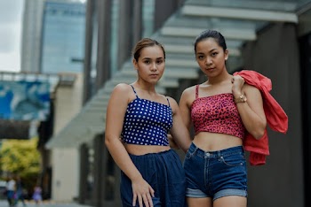 Selective focus  photography of two women in red and blue in front of a gray building