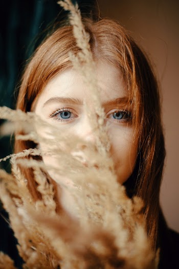 Selective Focus Photography of Woman Hiding Behind Flowers