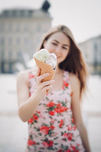 selective focus photography of woman holding ice cream in cone