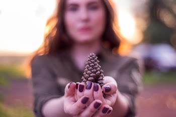 Selective Focus Photography of Woman Holding Pinecone