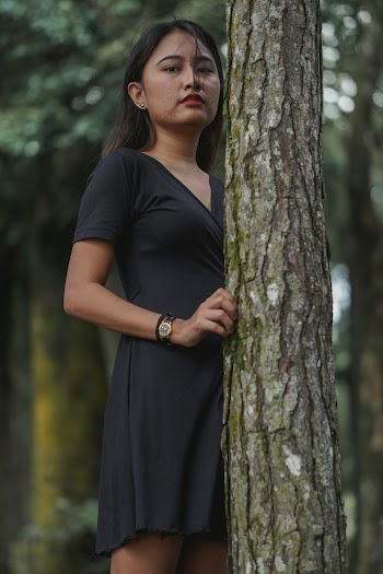 Selective Focus Photography Of Woman In Black V-neck Dress Standing Beside Tree