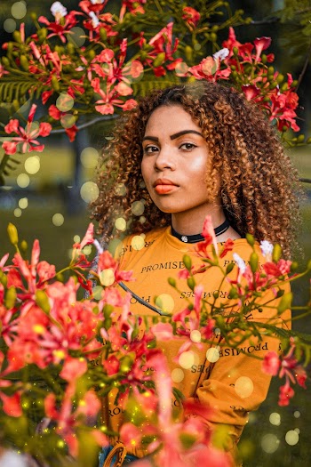 Selective Focus Photography of Woman in Casual Top Standing Behind A Red Flowering Tree