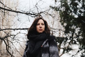selective focus photography of woman in gray coat under bare tree