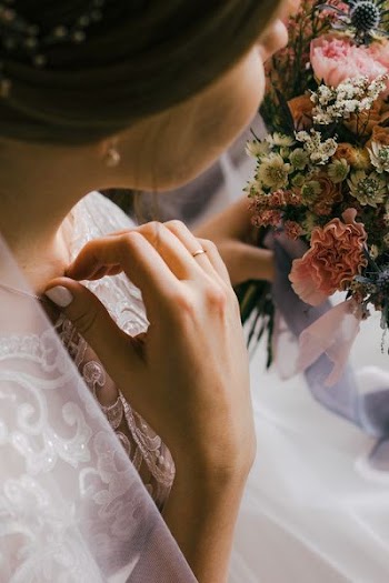 selective focus photography of woman in wedding dress holding flower