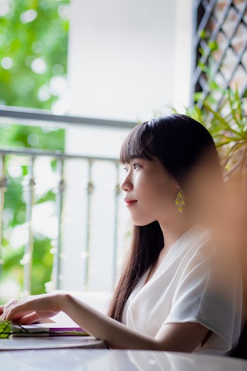 Selective Focus Photography of Woman in White Short-sleeved Shirt Sitting at Table