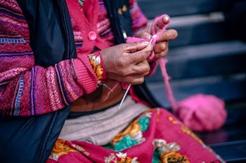 selective focus photography of woman knitting pink yarn