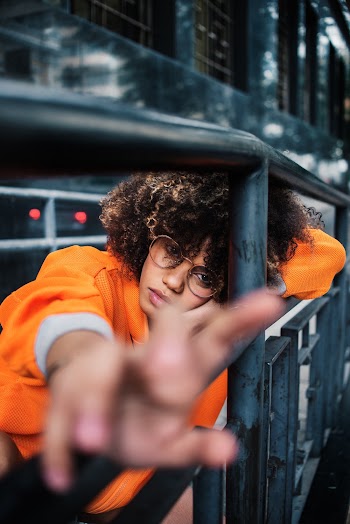 Selective Focus Photography of Woman Leaning On Black Metal Guardrail