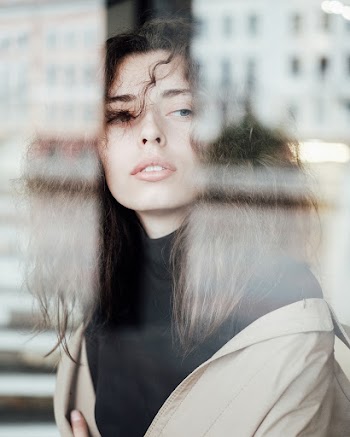Selective Focus Photography of Woman Sitting Beside Glass Wall