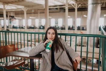 Selective Focus Photography Of Woman Sitting Beside Metal Rail