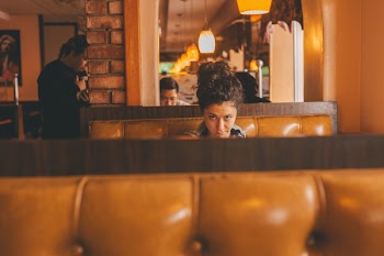 Selective Focus Photography of Woman Sitting in Middle of Bench Inside Building