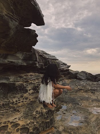 Selective Focus Photography of Woman Sitting on Rock Formation