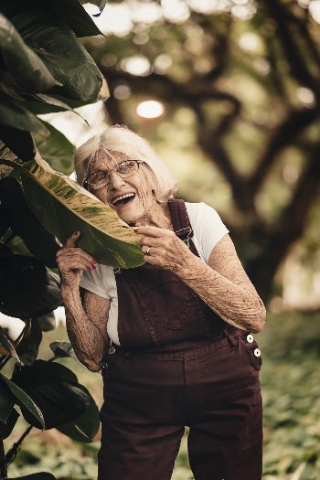 Selective Focus Photography of Woman Smiling Holding Green Leaf