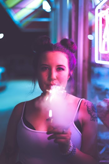 Selective Focus Photography of Woman Smoking Standing Beside Wall
