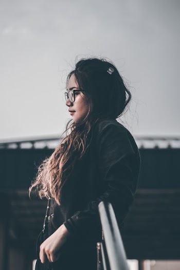 selective focus photography of woman standing beside railing