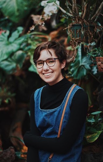 selective focus photography of woman standing in front of plants