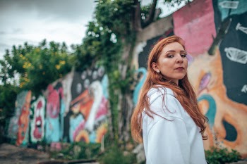 Selective Focus Photography of Woman Standing in Front of Wall With Mural