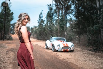 Selective Focus Photography of Woman Standing on Road Near White Coupe