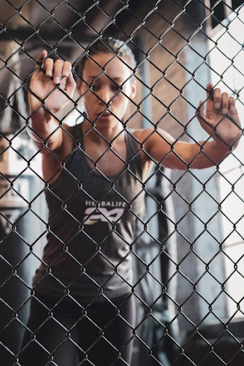 Selective Focus Photography Of Woman Touching Fence