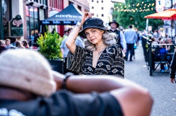 Selective Focus Photography of Woman Wearing Black and White Top Posing For a Photo on the Street