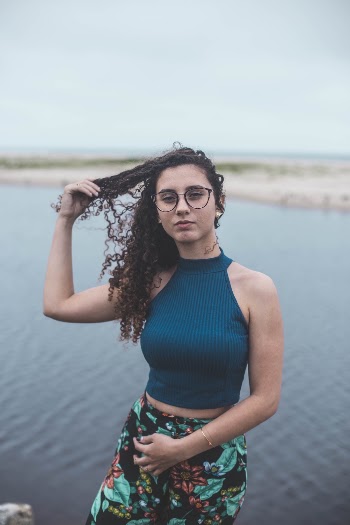 Selective Focus Photography of Woman Wearing Blue Halter Crop Top and Blue-and-black Floral Bottoms Near Body of Water