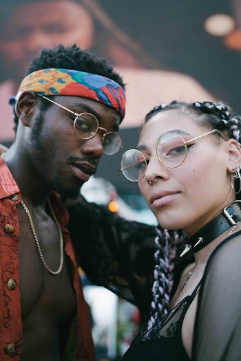 Selective Focus Photography of Woman Wearing Eyeglasses Putting Right Hand on Man's Neck
