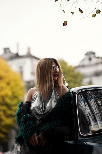 Selective Focus Photography of Woman Wearing Silver V-neck Sleeveless Top Leaning on Black Car