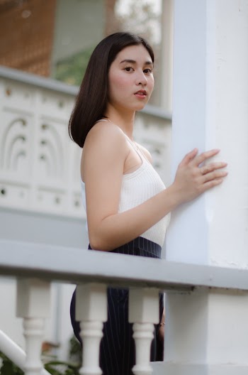 Selective Focus Photography of Woman Wearing White Crop Top Standing Beside Concrete Rail