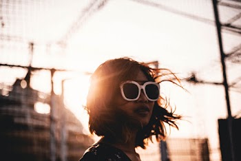 Selective Focus Photography of Woman Wearing White Sunglasses Beside Mesh Fence