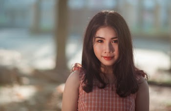 Selective Focus Photography of Woman With Pink and White Sleeveless Top Standing Behind Tree Trunk