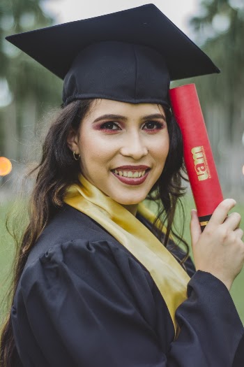 Selective Focus Portrait Photo of Smiling Woman in Black Academic Dress Holding Diploma Posing